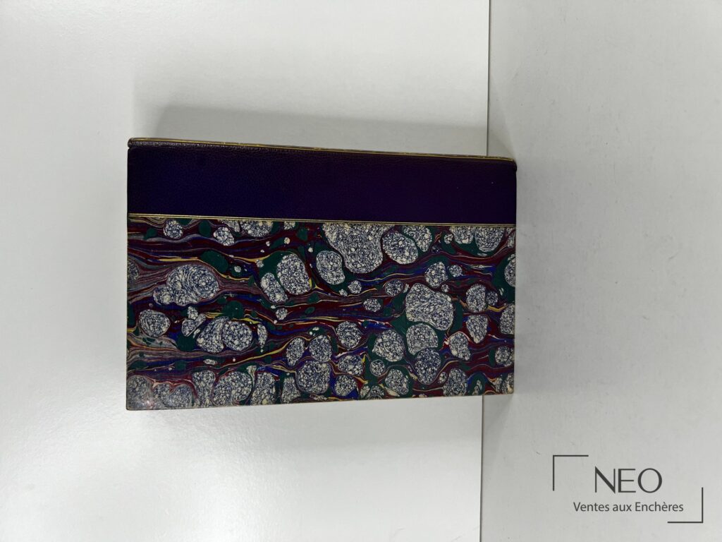 Couverture d'un livre relié en demi basane violette avec papier marbré multicolore.