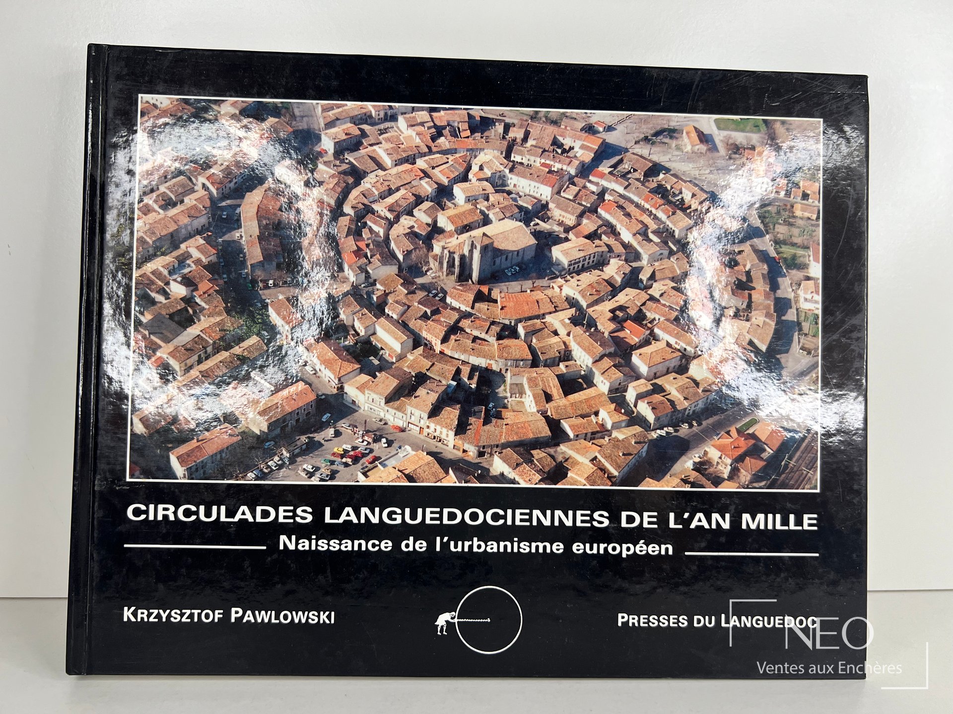 Couverture rigide noire illustrée d'une vue aérienne d'un village circulaire