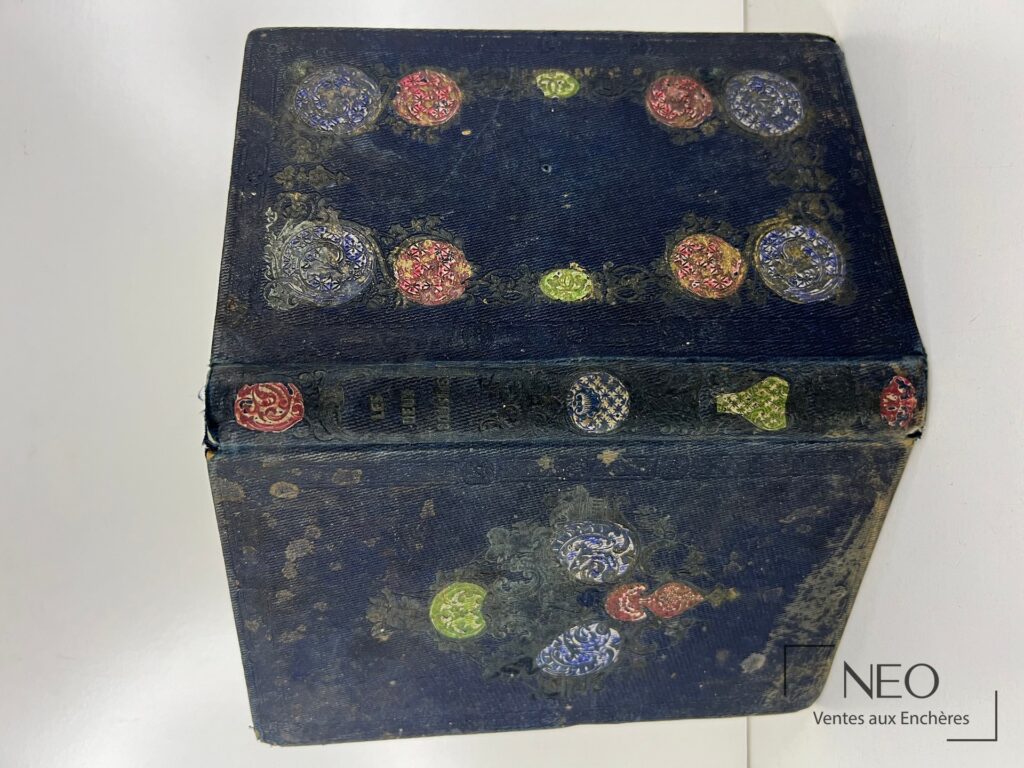 Couverture bleue ornée de motifs circulaires polychromes et d’usures visibles