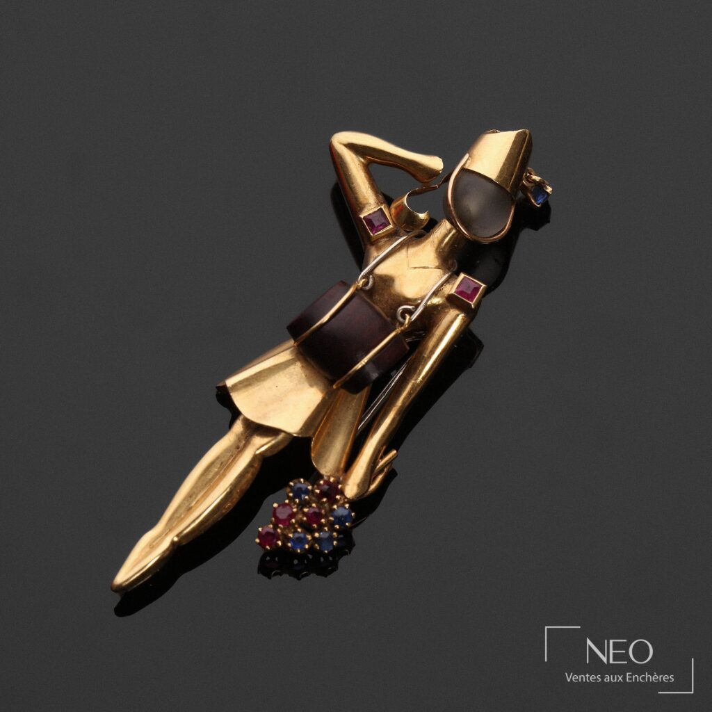 Broche figurant une Madelon en or jaune avec pierres rouges et bleues sur fond noir