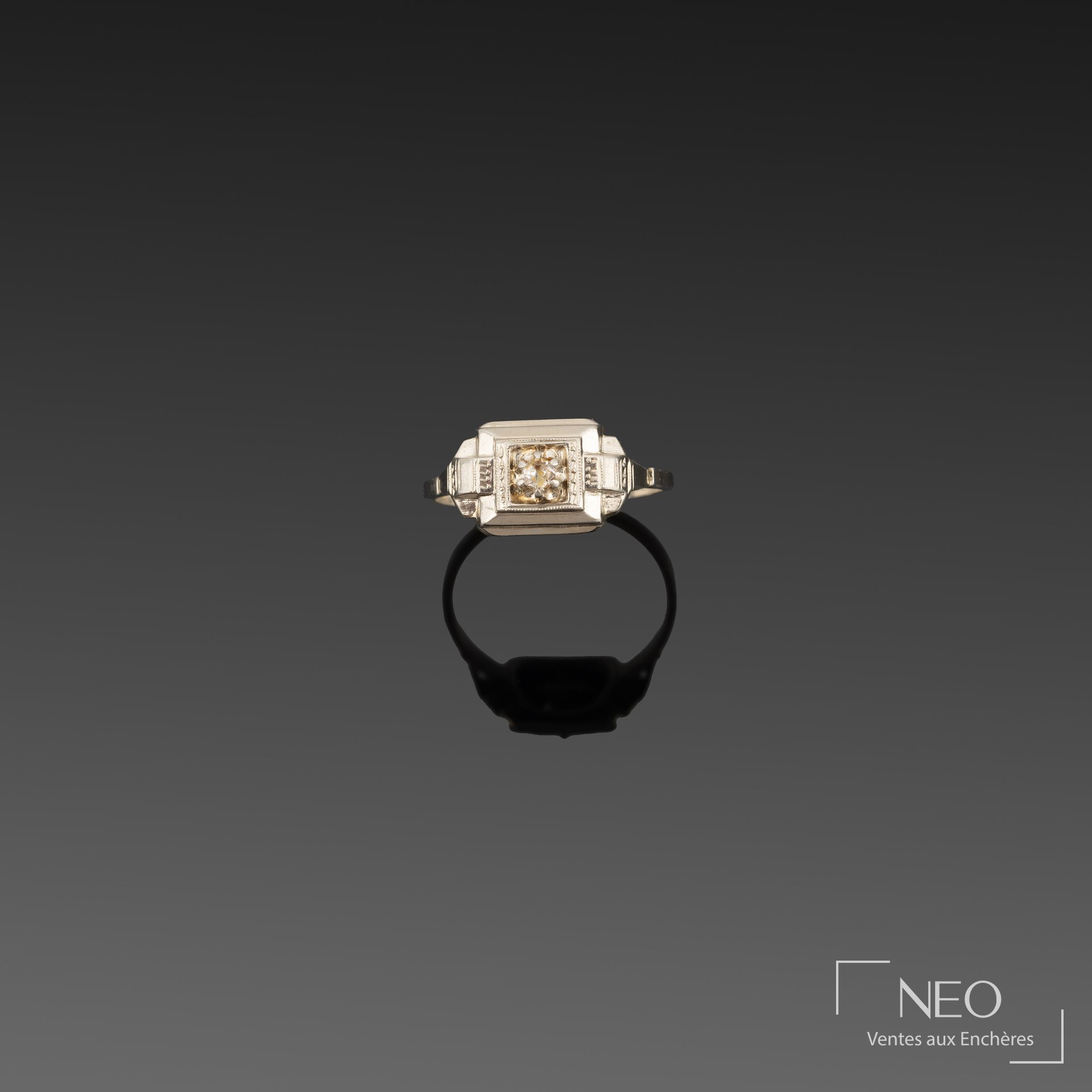 Bague de style Art Déco en or gris avec petit diamant central sur fond sombre