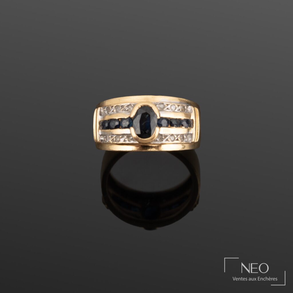 Bague bandeau en or jaune sertie d’un saphir central et de pierres bleues et blanches