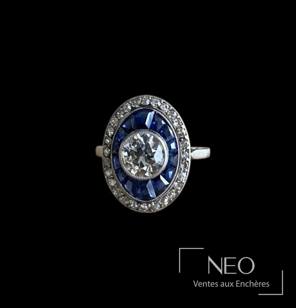 Bague Belle Epoque en platine avec diamant central et entourage de saphirs bleus
