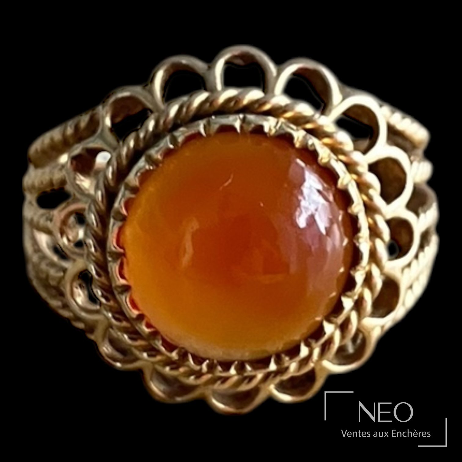 Bague dôme en or jaune avec cabochon orange centré sur un fond noir