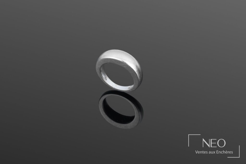 Bague jonc bombée en or gris présentée de face sur fond sombre