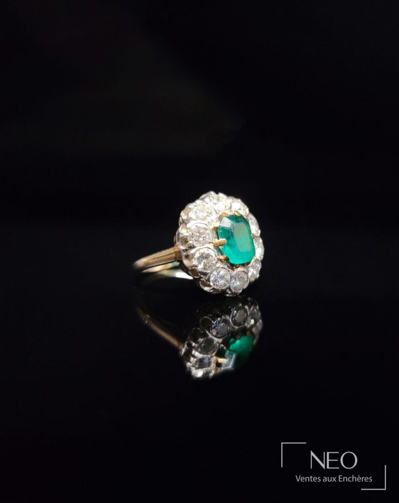 Bague marguerite avec émeraude centrale et entourage de diamants sur fond noir