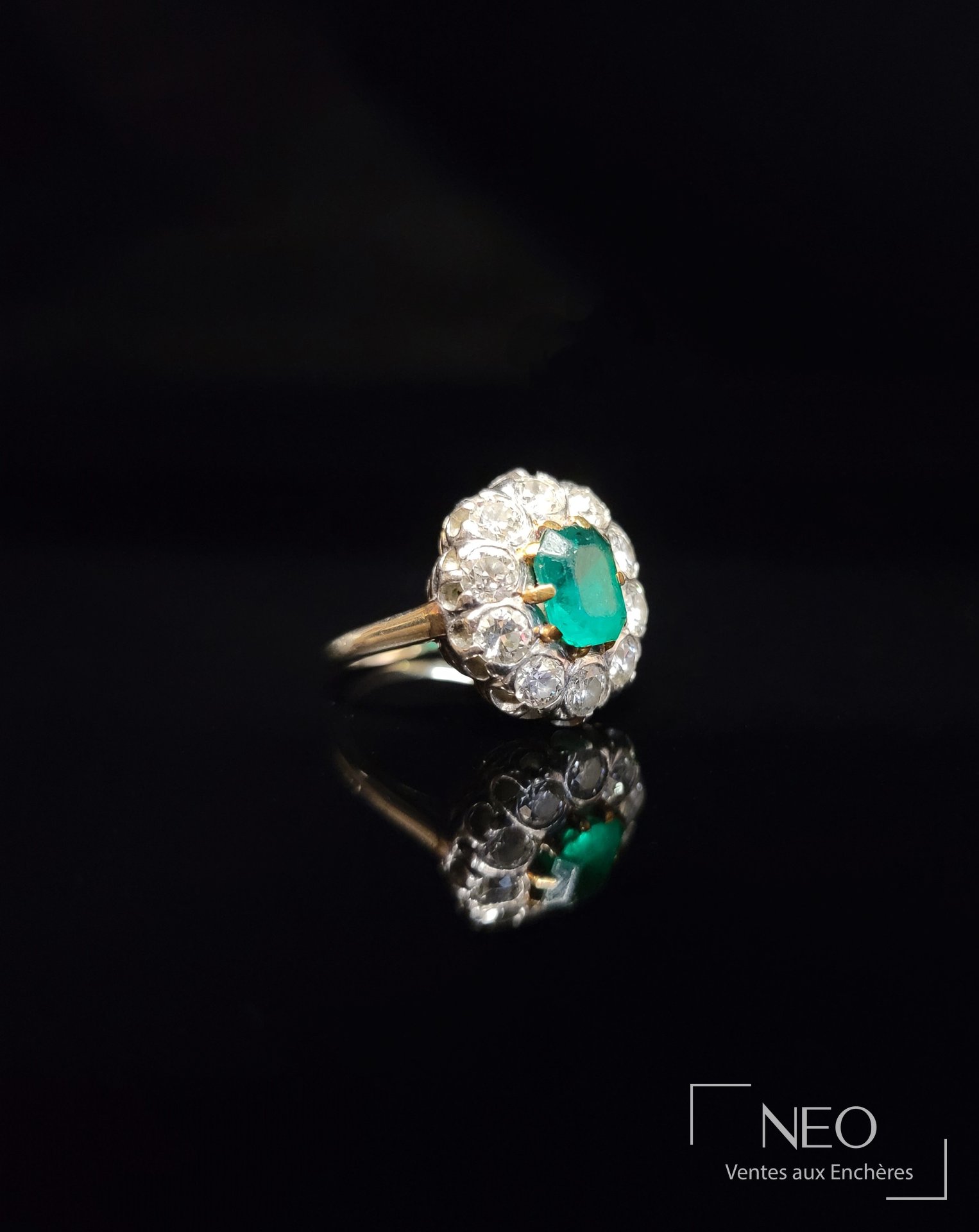 Bague marguerite avec émeraude centrale et entourage de diamants sur fond noir