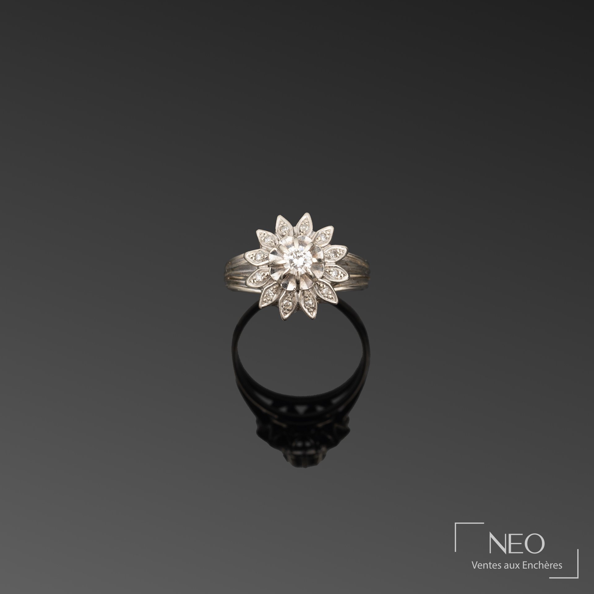 Bague marguerite en or gris avec diamant central et pétales pavés de brisures de diamant
