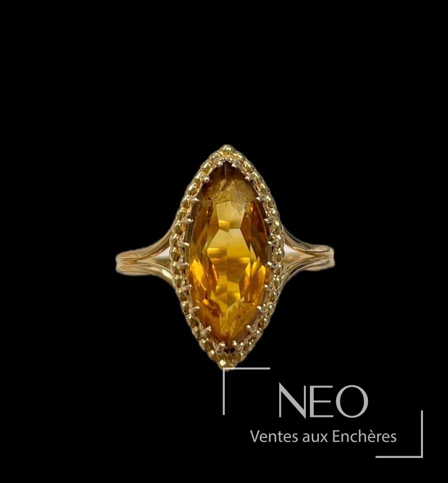Bague marquise en or jaune avec pierre orangée facettée sur fond noir