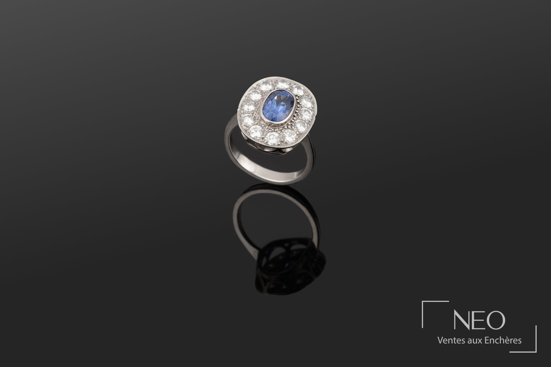 Bague en or blanc sertie d’un saphir ovale entouré de brillants