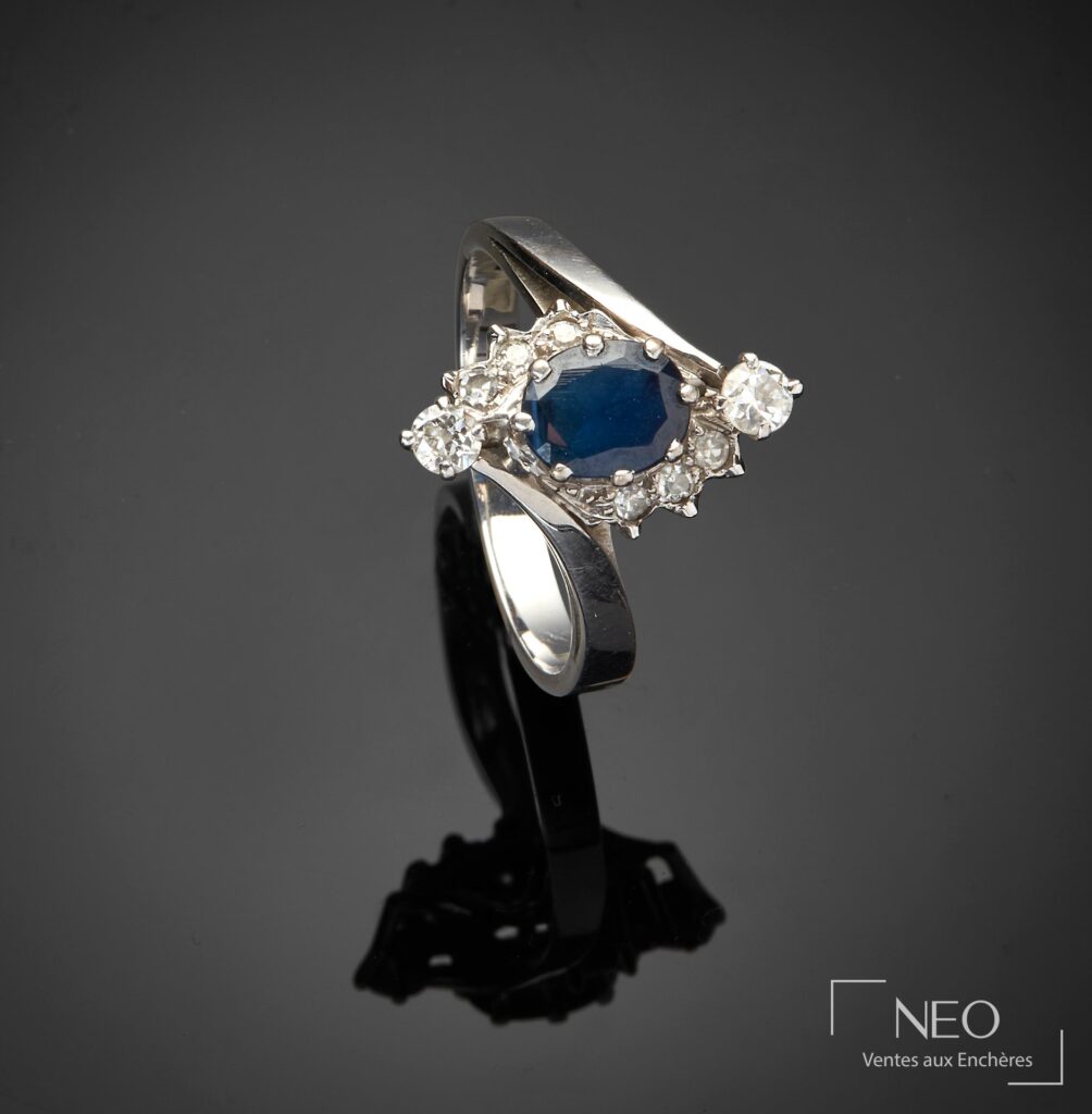 Bague en or gris avec pierre bleue centrale et entourage de pierres blanches