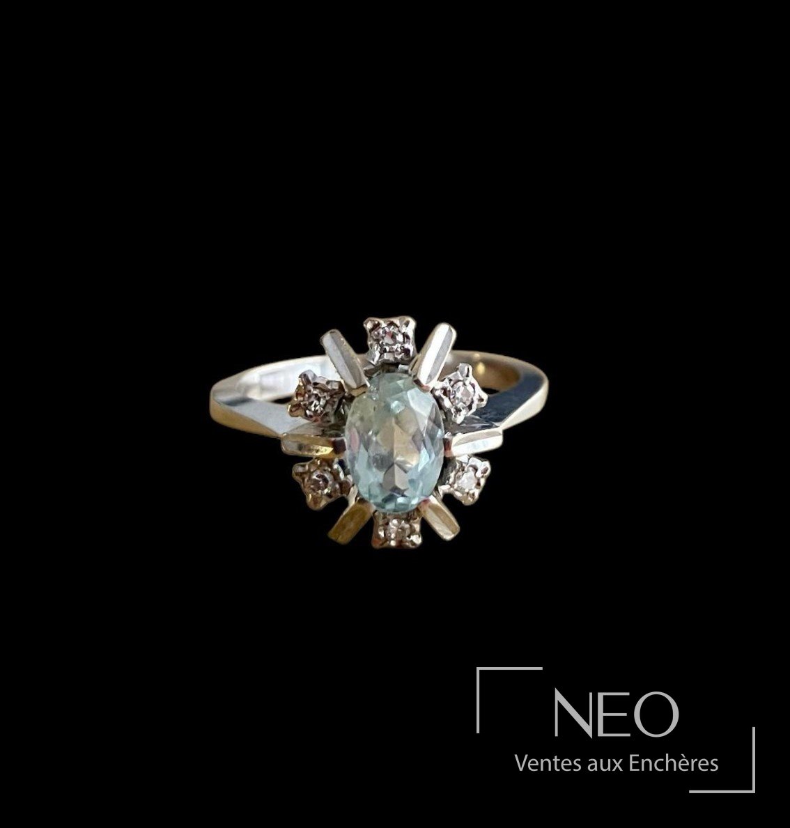 Bague en or gris sertie d’une pierre bleue ovale entourée de brillants