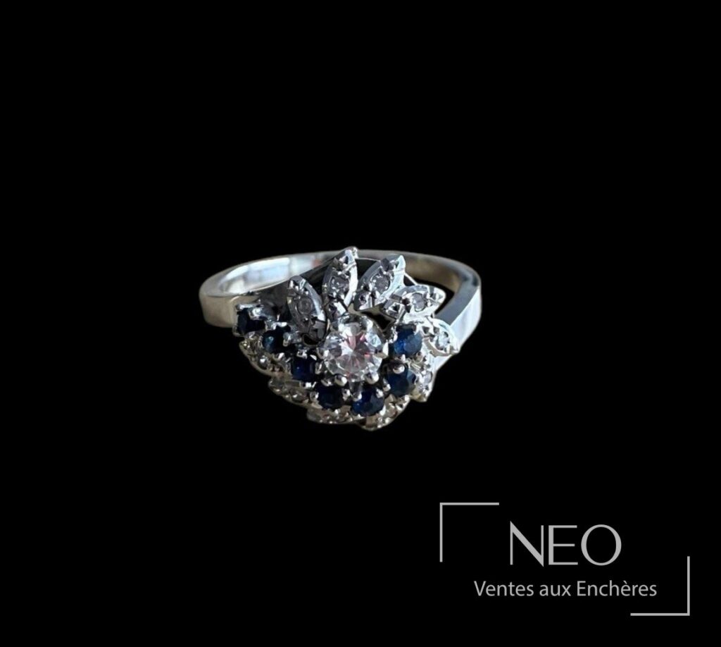 Bague en or gris avec plateau floral serti d’un diamant central et de pierres bleues