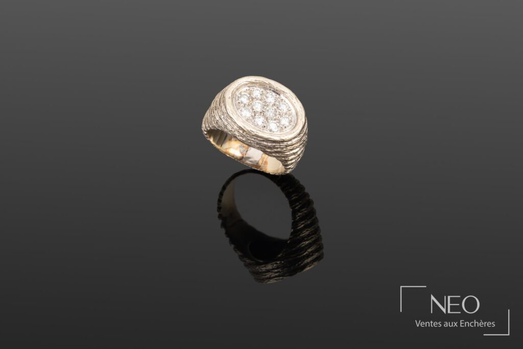 Bague en or gris à plateau ovale pavé de diamants sur fond sombre