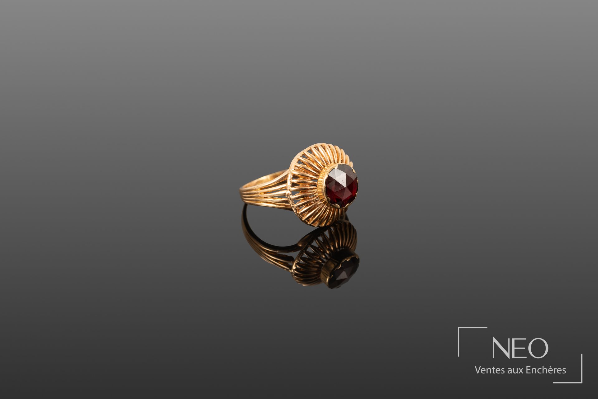 Bague en or jaune 18 carats retenant une pierre rouge