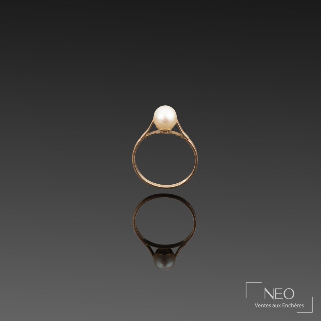 Bague en or jaune sur fond sombre avec perle de culture blanche en serti
