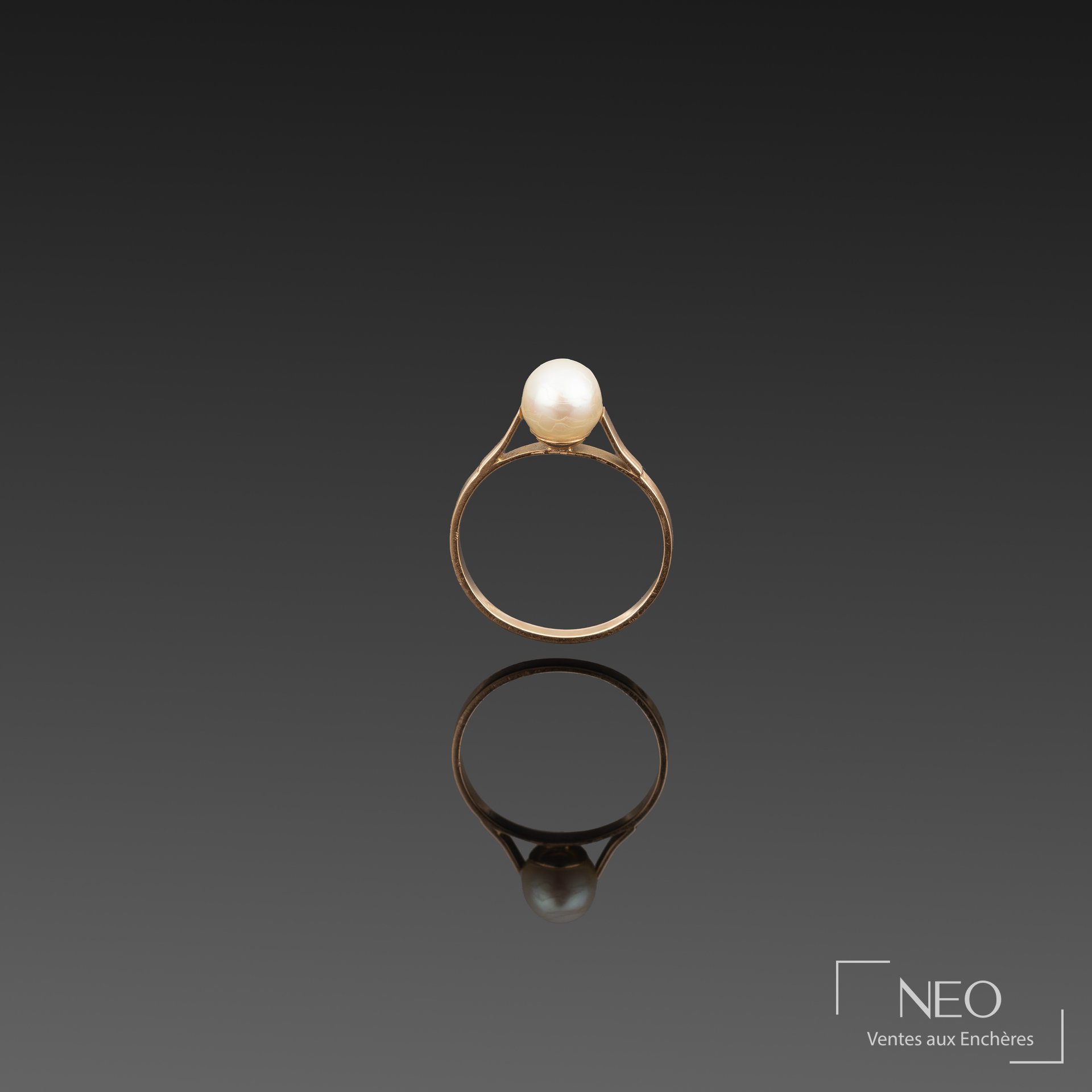 Bague en or jaune sur fond sombre avec perle de culture blanche en serti
