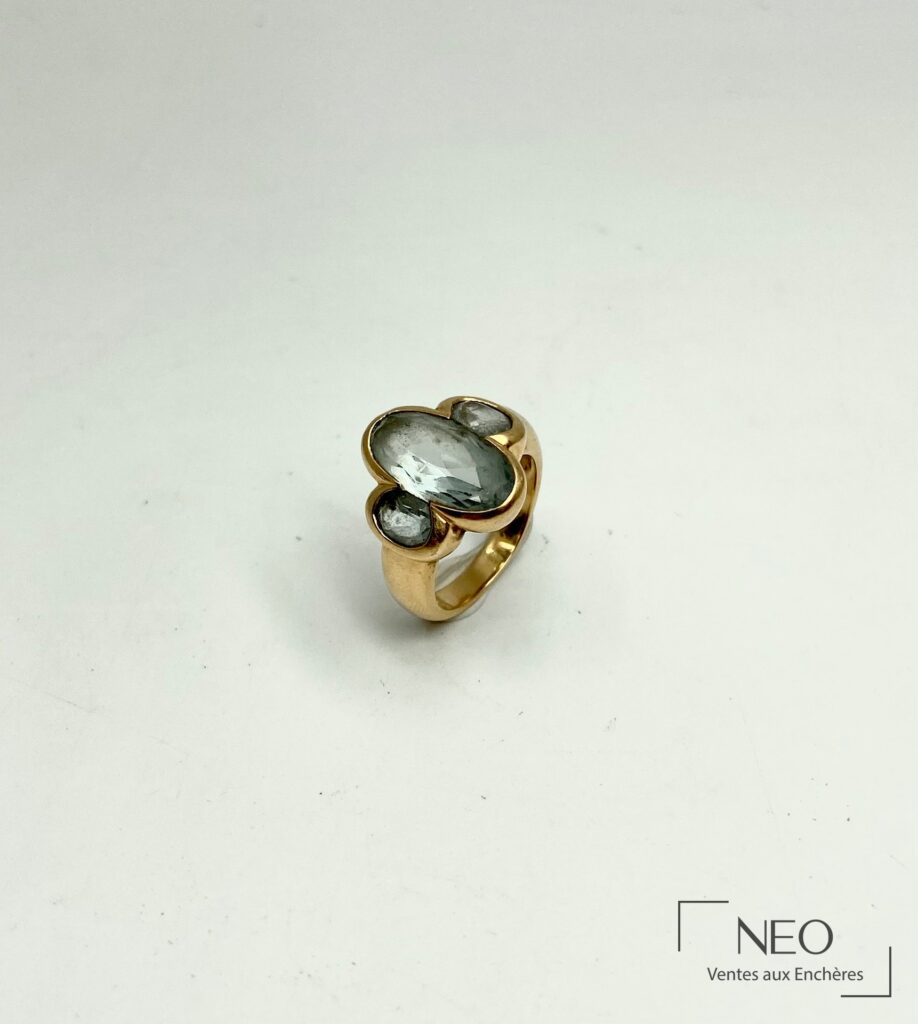Bague en or jaune ornée de trois aigues-marines sur fond blanc