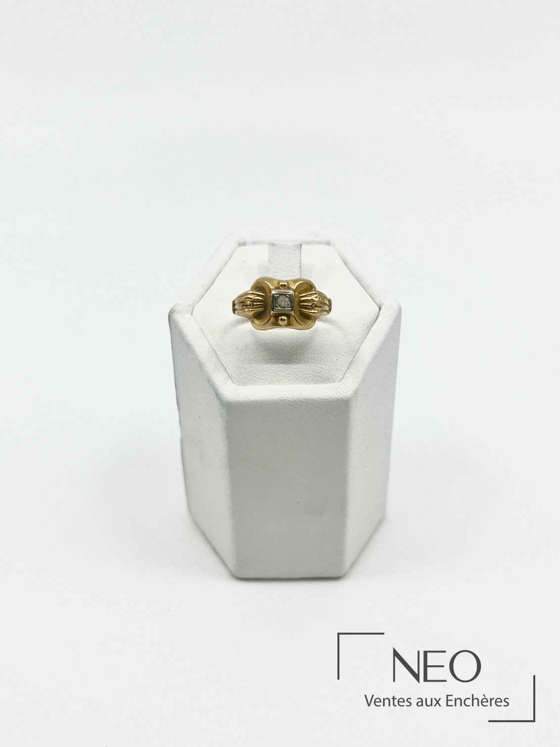 Bague en or jaune de style Art Déco avec pierre blanche centrale sur présentoir