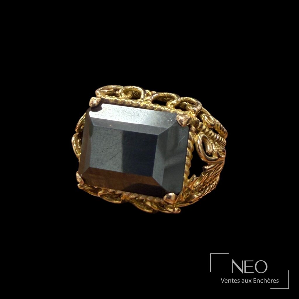 Bague en or jaune avec pierre noire centrale sur fond noir