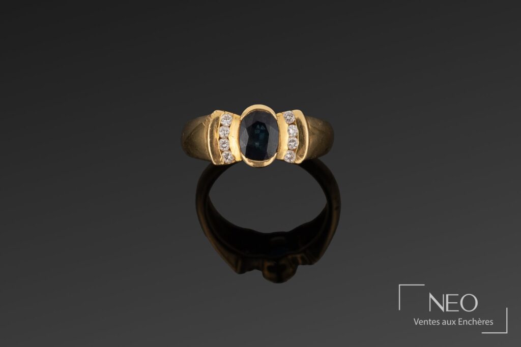 Bague en or jaune avec saphir ovale et diamants sur fond sombre