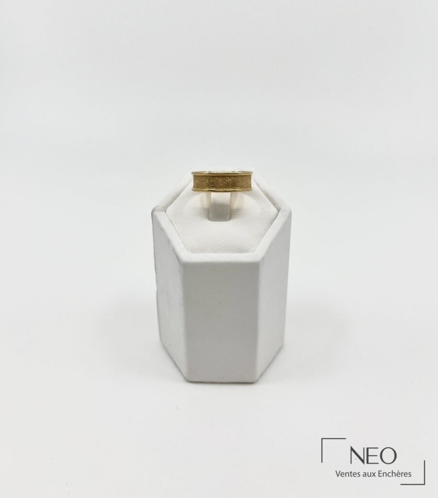 Bague ruban en or jaune sur support blanc