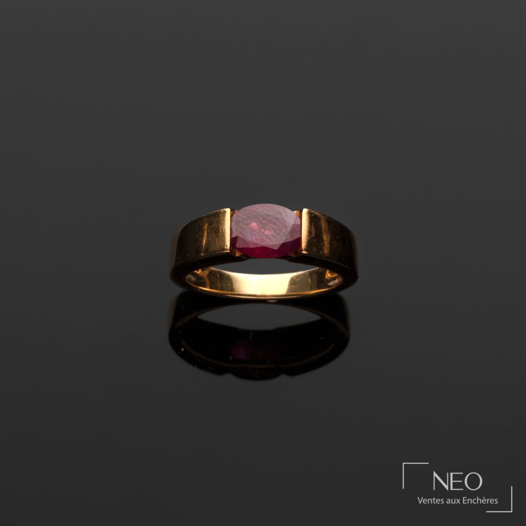 Bague ruban en or jaune avec rubis central sur fond sombre