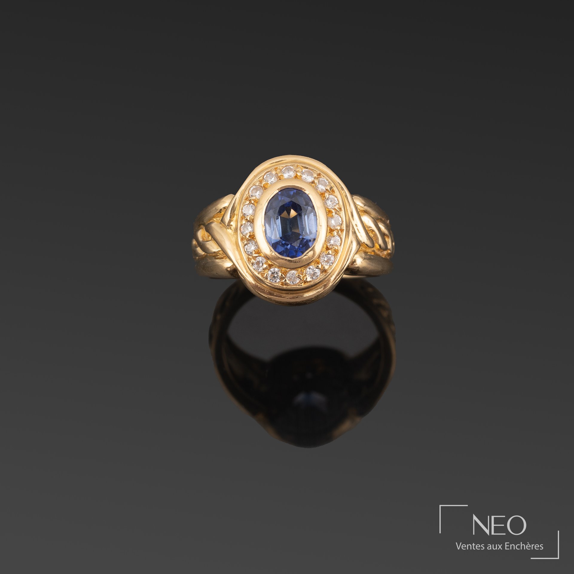Bague en or jaune ornée d’un saphir ovale entouré de brillants