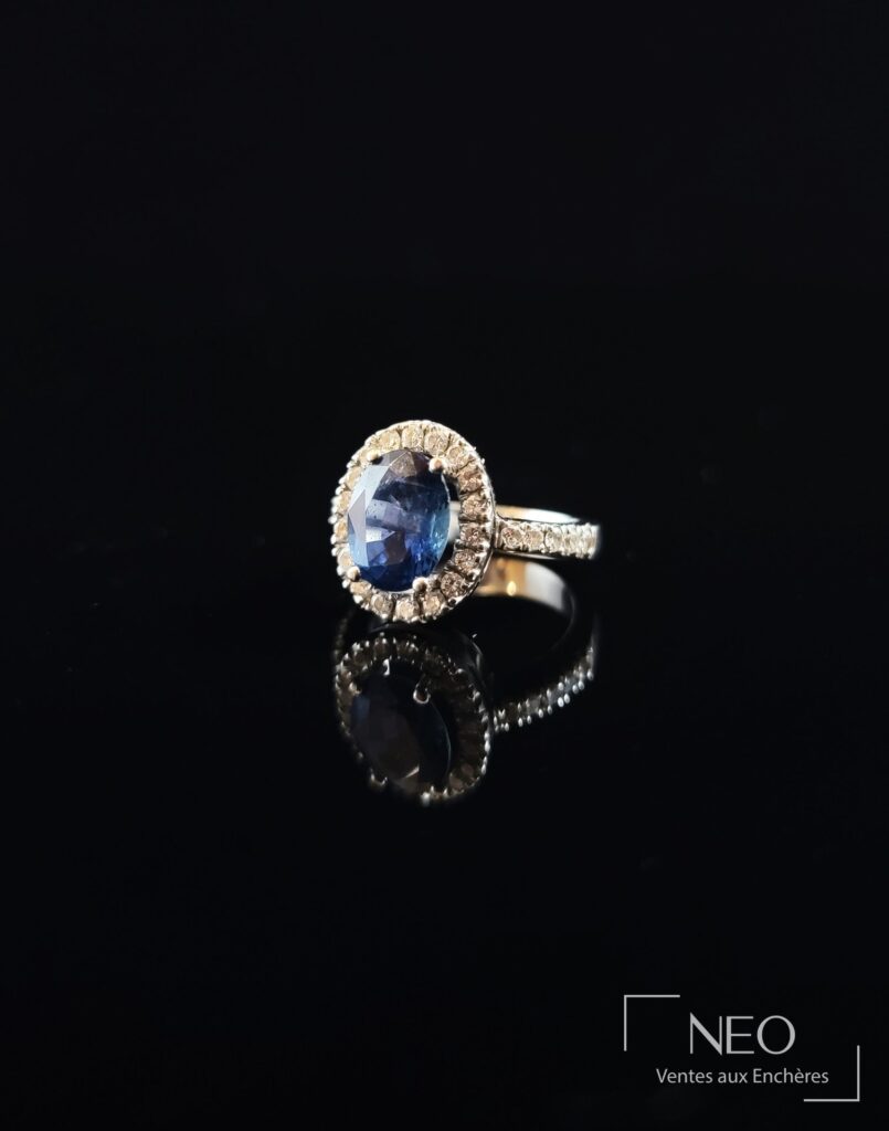 Bague en or gris sertie d’un saphir ovale entouré de diamants