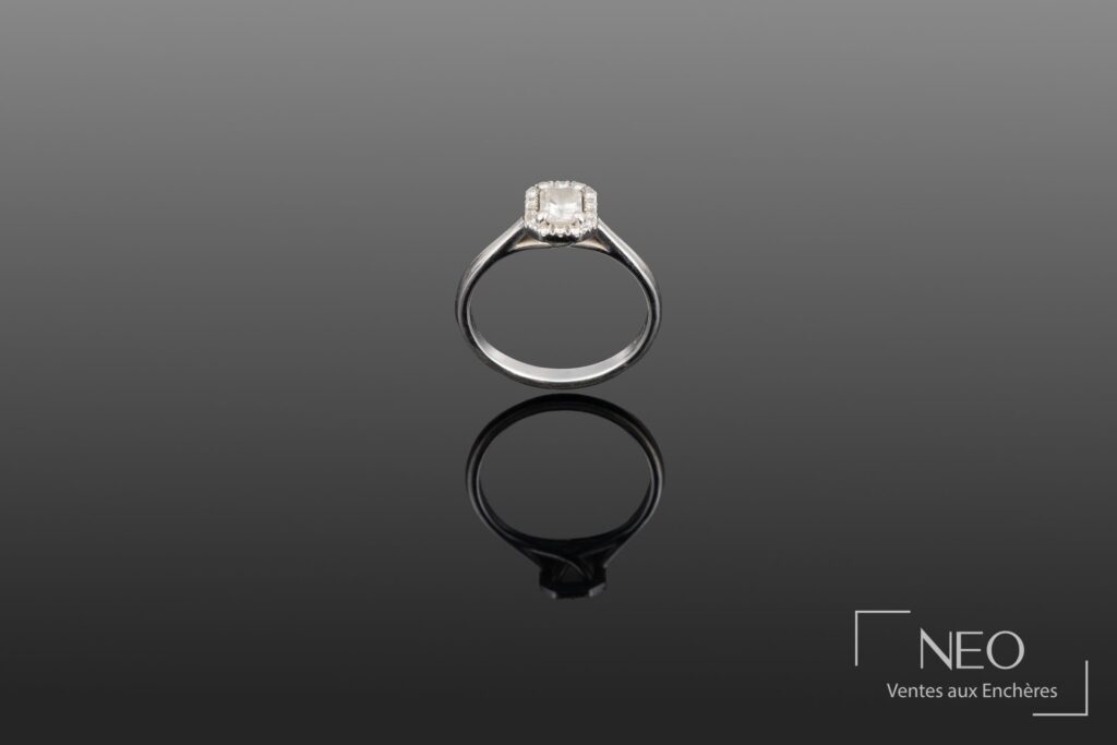 Bague solitaire en or gris avec diamant central et entourage de petits diamants