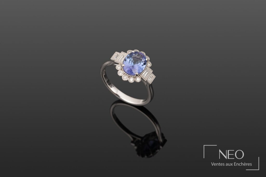Bague en or gris sertie d'une tanzanite ovale et de diamants sur fond sombre