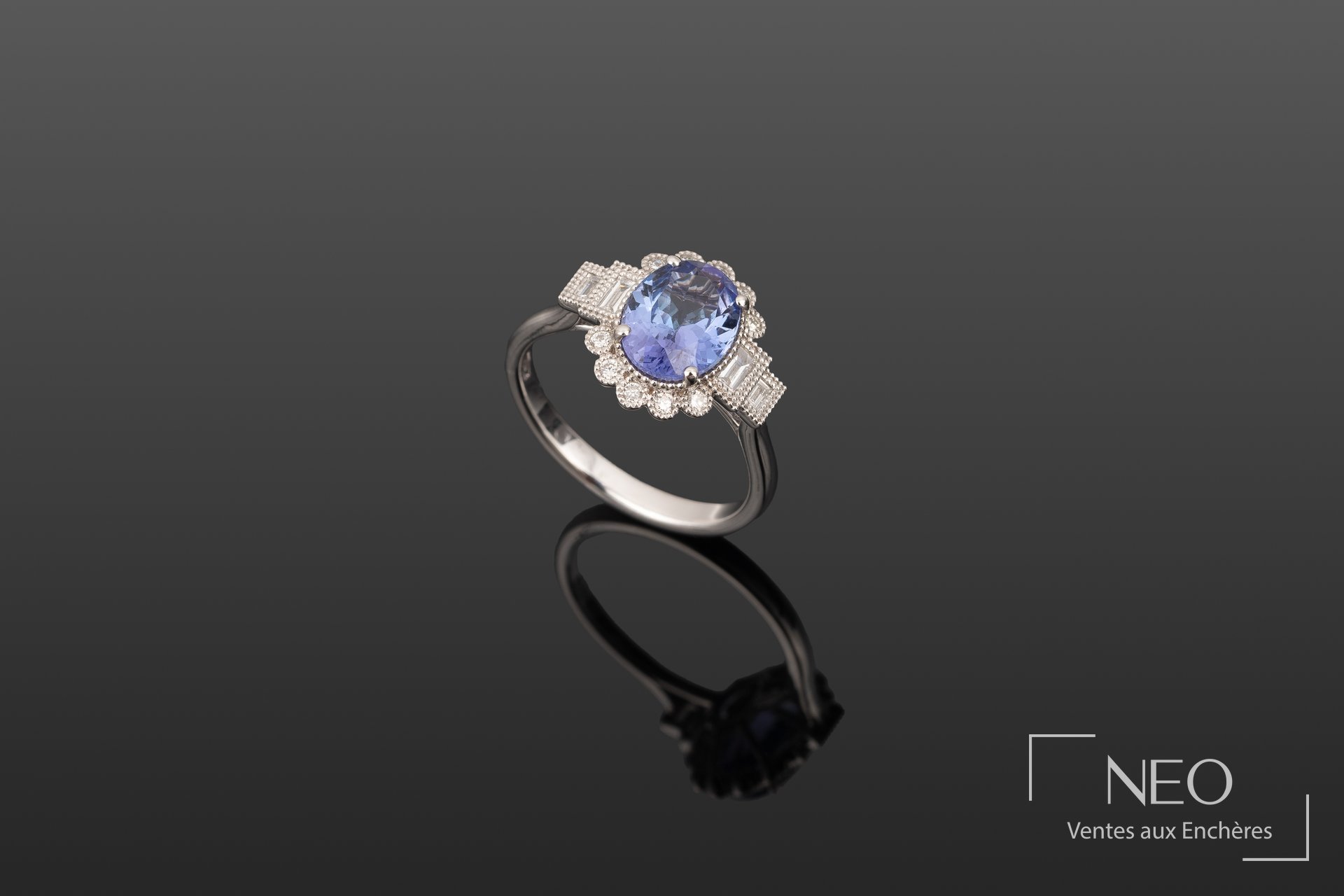 Bague en or gris sertie d'une tanzanite ovale et de diamants sur fond sombre