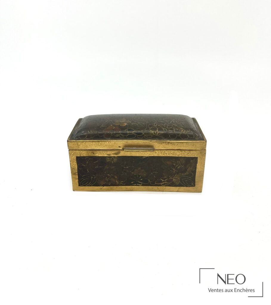 Boîte rectangulaire en métal doré ornée d'émaux cloisonnés floraux sur fond sombre.