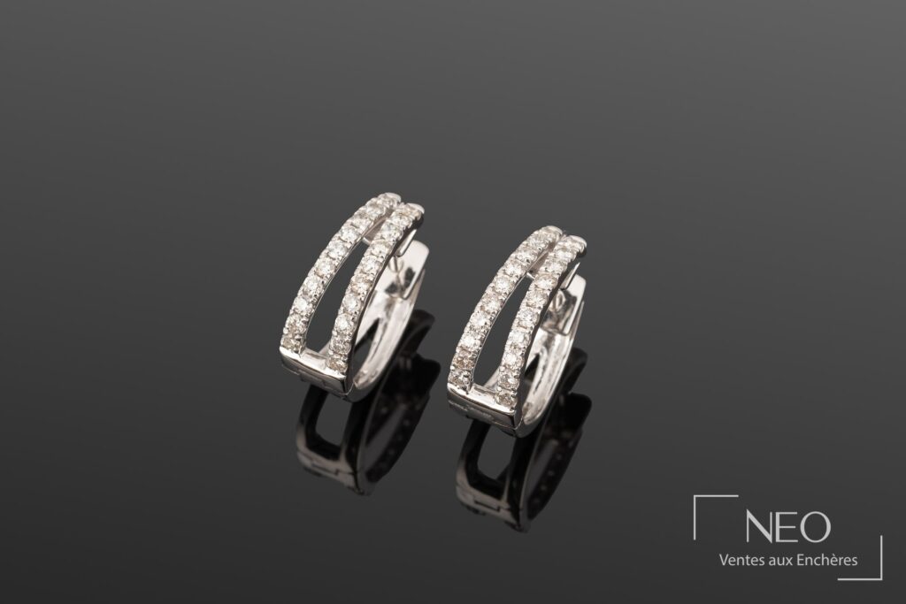 Paire de boucles d'oreille créoles en or gris serties de diamants sur fond sombre