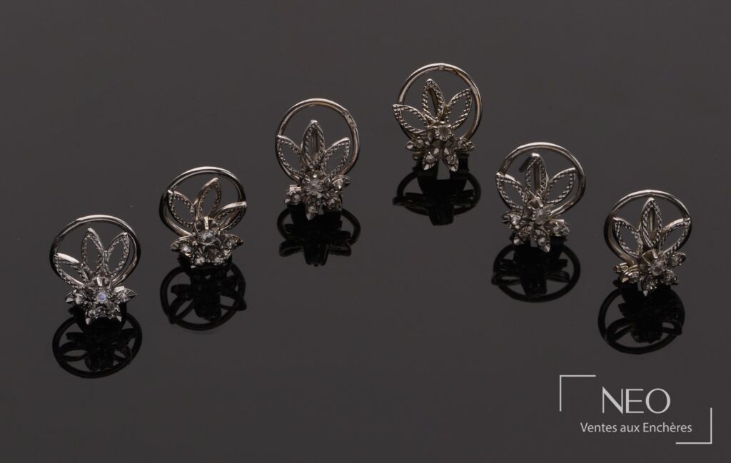 Six boucles d'oreille en or gris et diamants présentées sur fond sombre