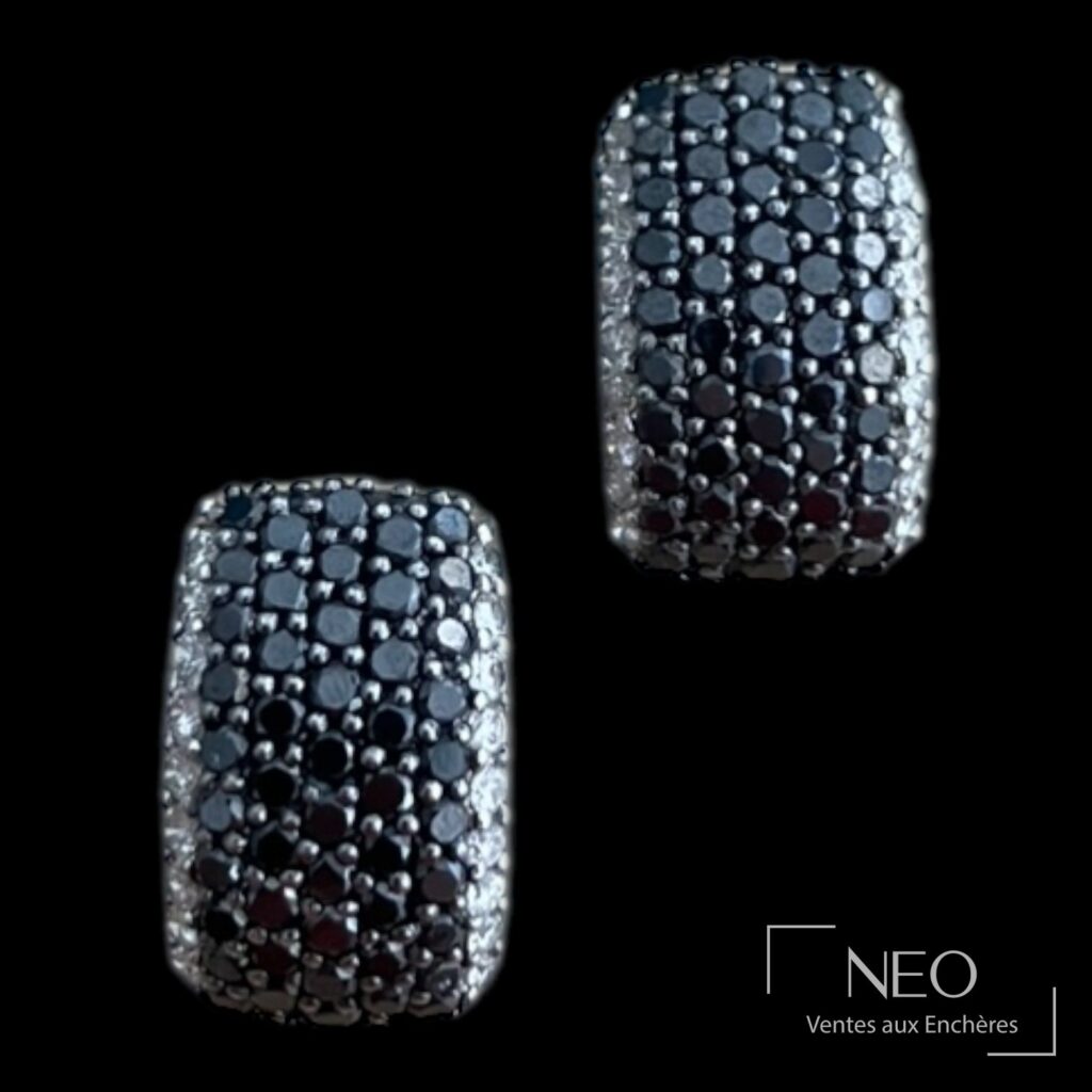 Paire de boucles d’oreille pavées de diamants noirs et blancs sur fond noir