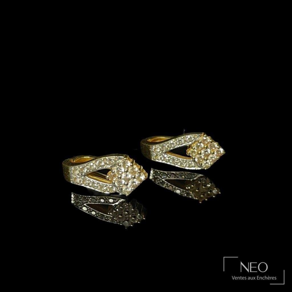 Paire de boucles d'oreilles en or jaune pavées de pierres blanches sur fond noir