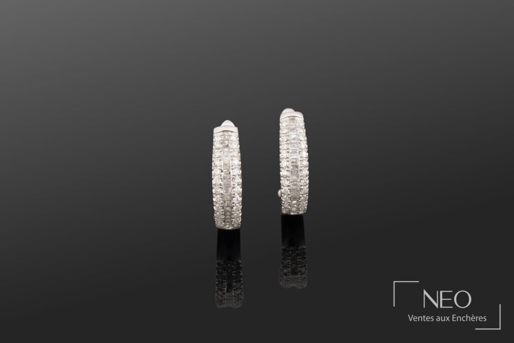 Paire de boucles d'oreilles créoles en platine serties de diamants sur fond sombre