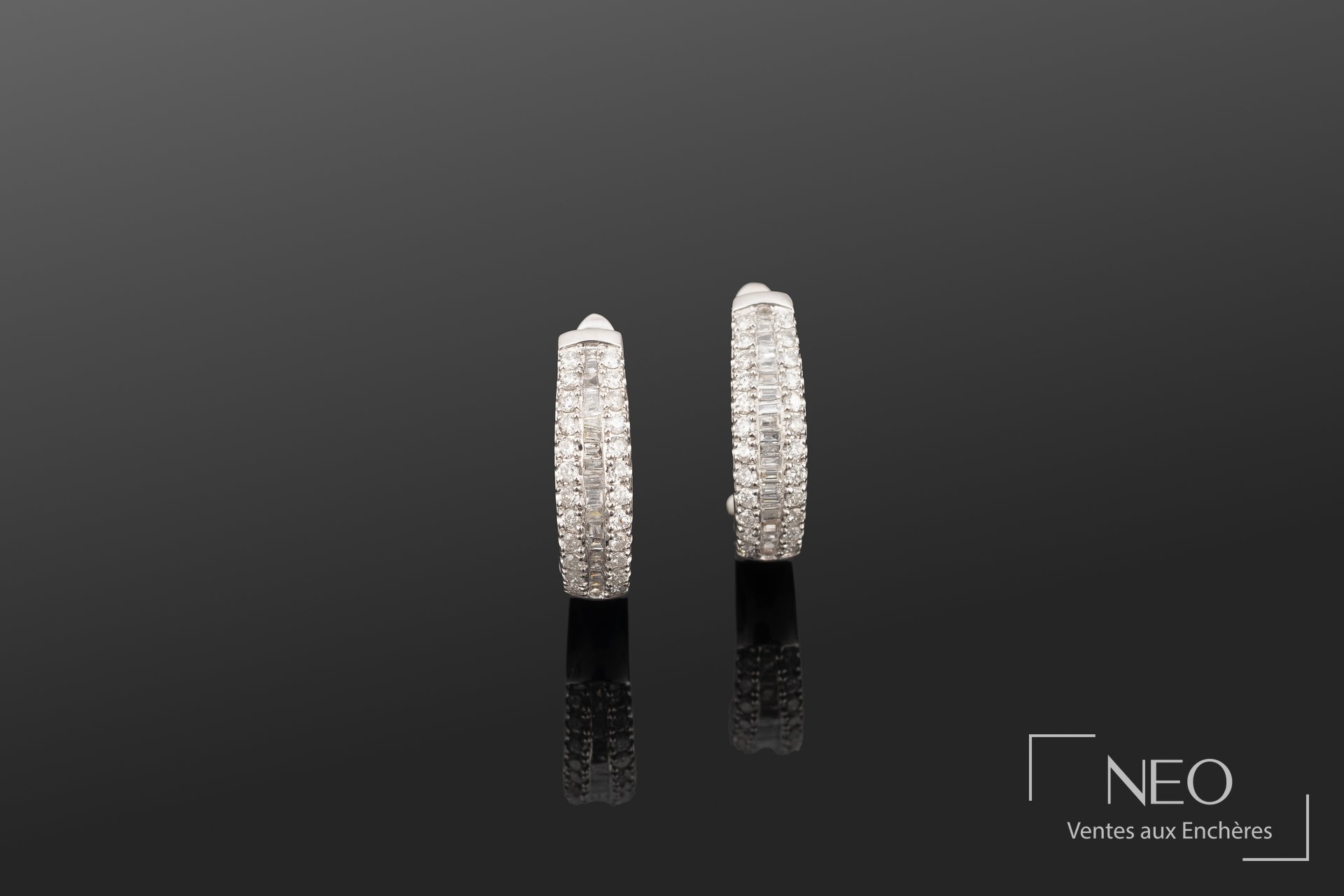Paire de boucles d'oreilles créoles en platine serties de diamants sur fond sombre