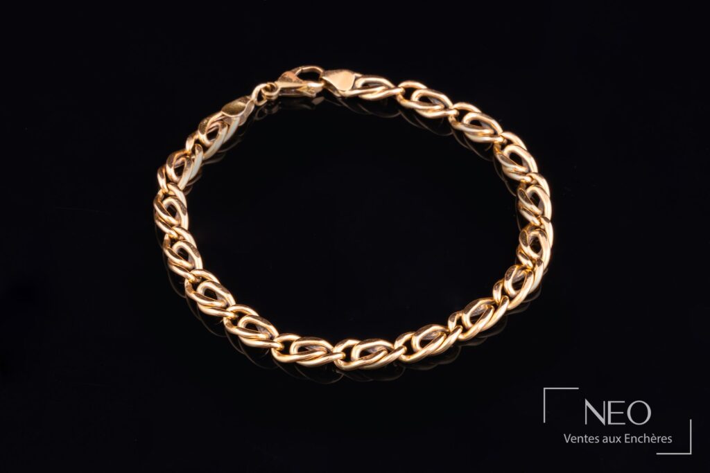 Bracelet en or à maille fantaisie posé sur fond noir