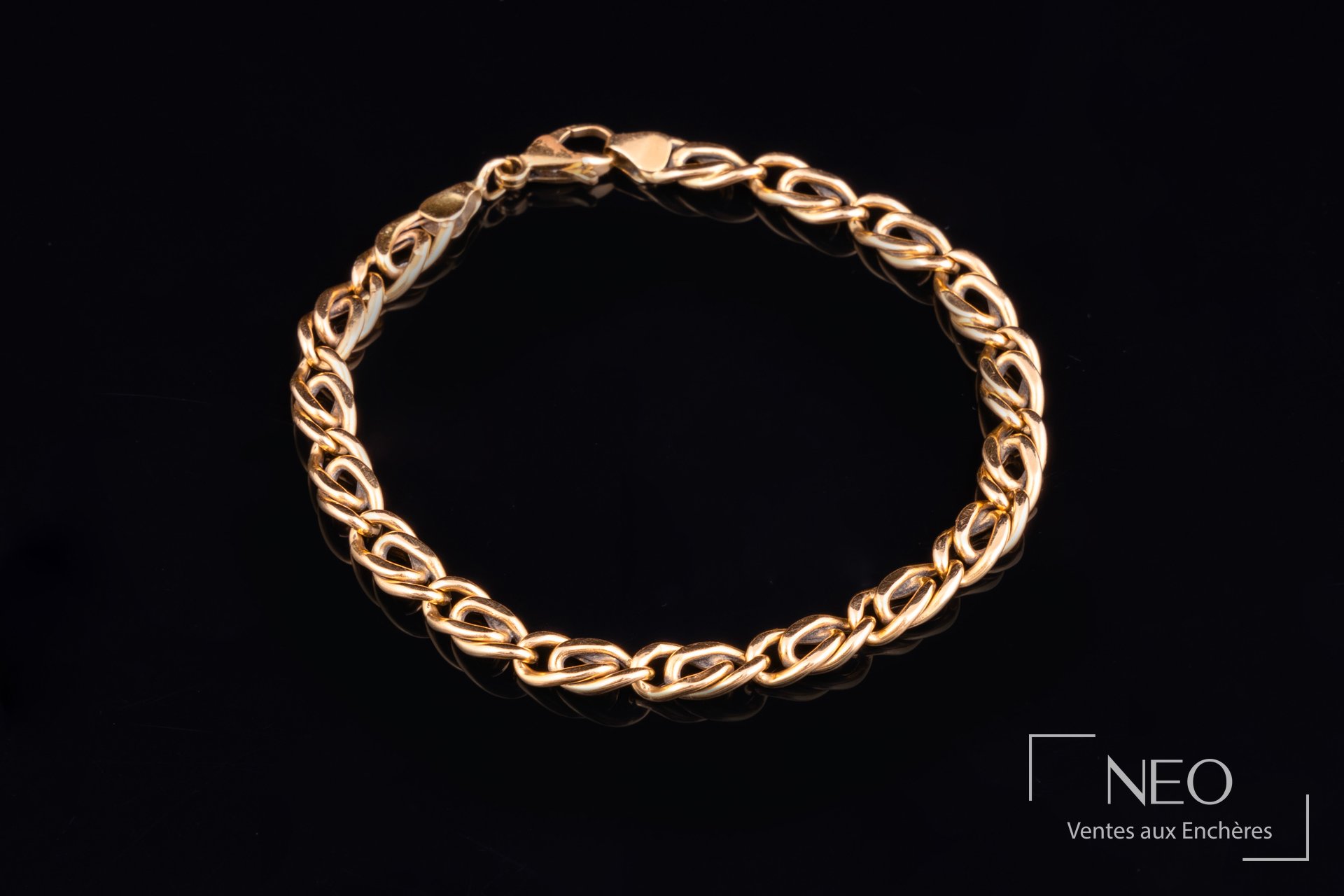 Bracelet en or à maille fantaisie posé sur fond noir