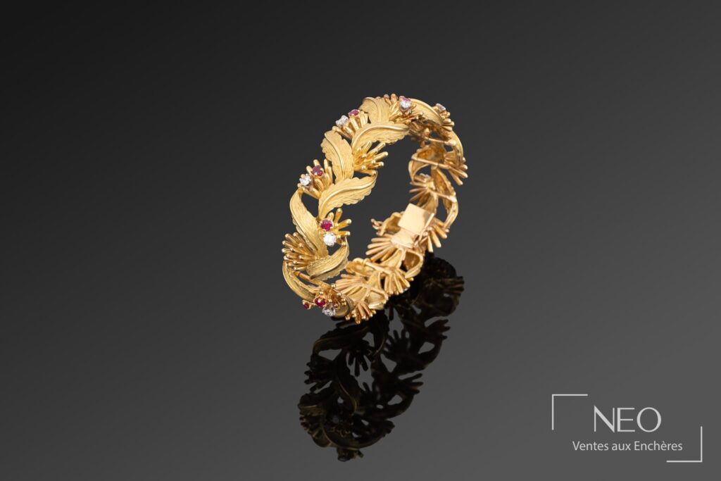 Bracelet articulé en or jaune orné de diamants et de rubis sur fond sombre
