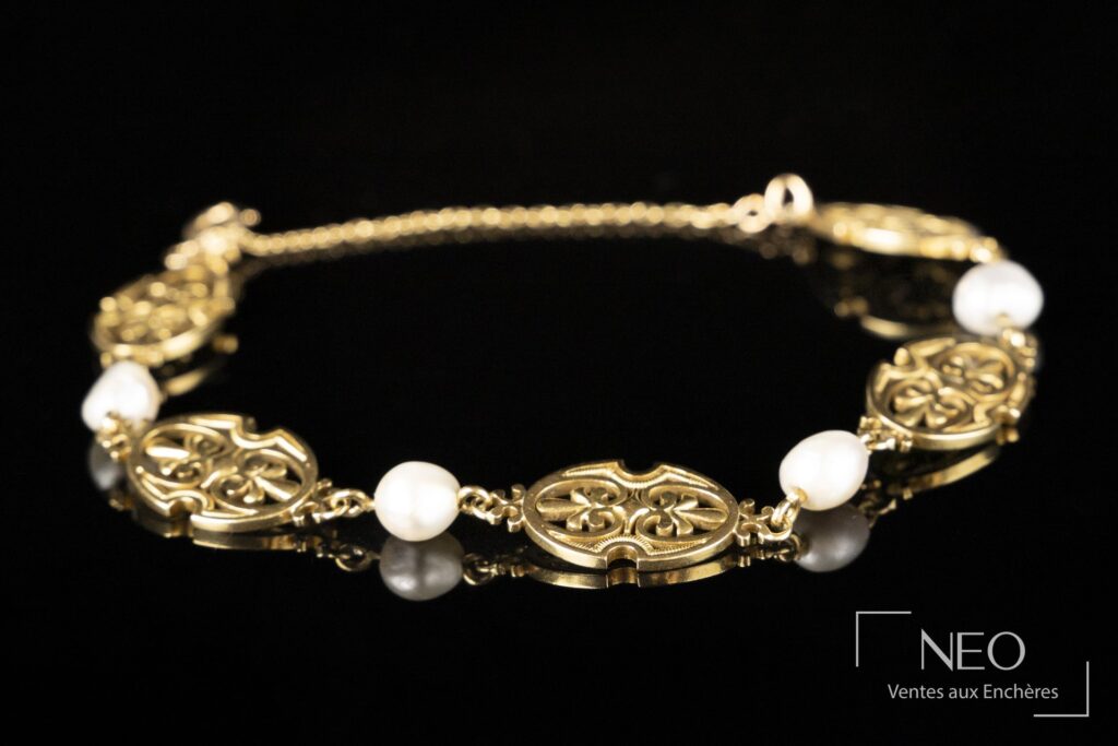 Bracelet en or jaune à volutes et perles baroques blanches sur fond noir