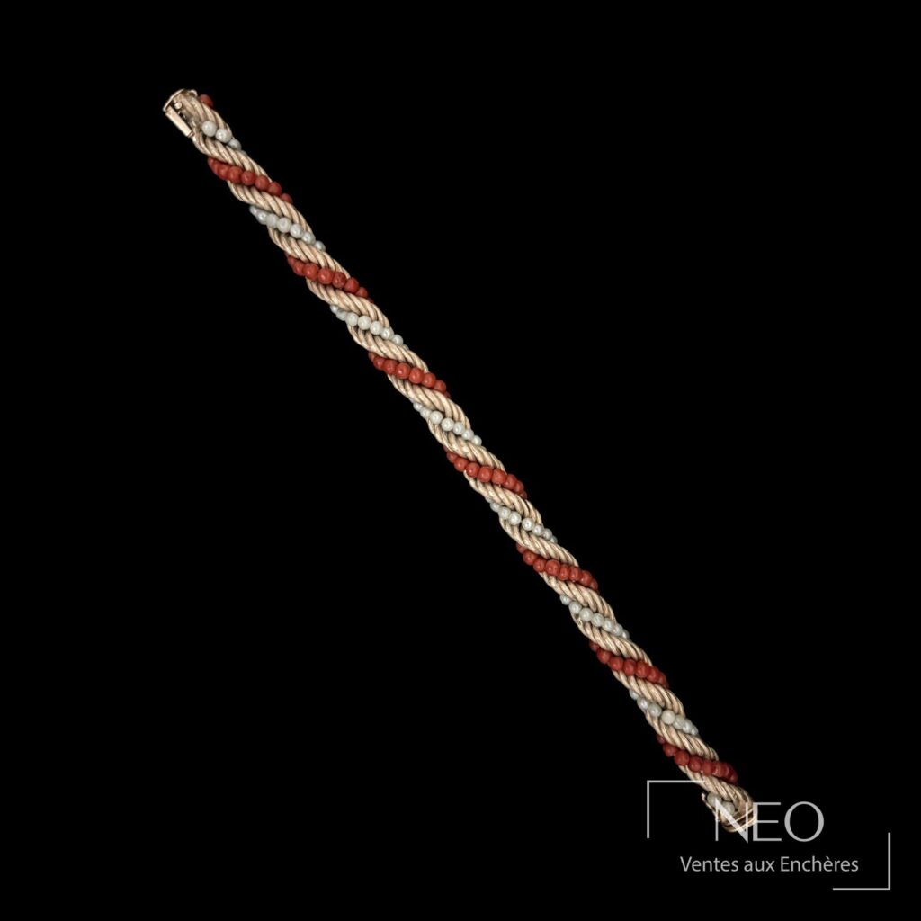 Bracelet torsadé en or jaune avec alternance de perles rouges et blanches sur fond noir