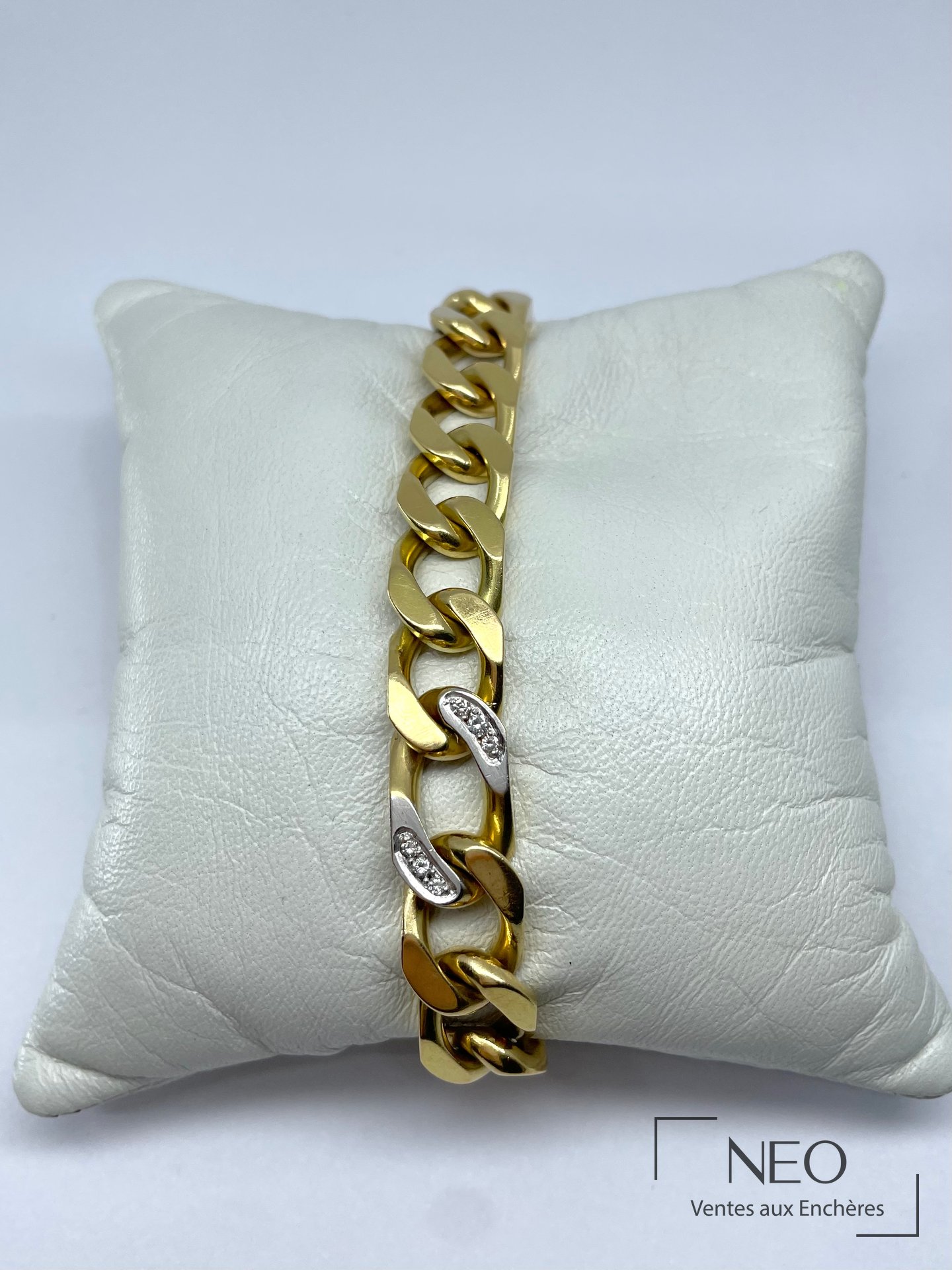 Bracelet gourmette en or jaune avec deux maillons sertis de diamants sur coussin blanc