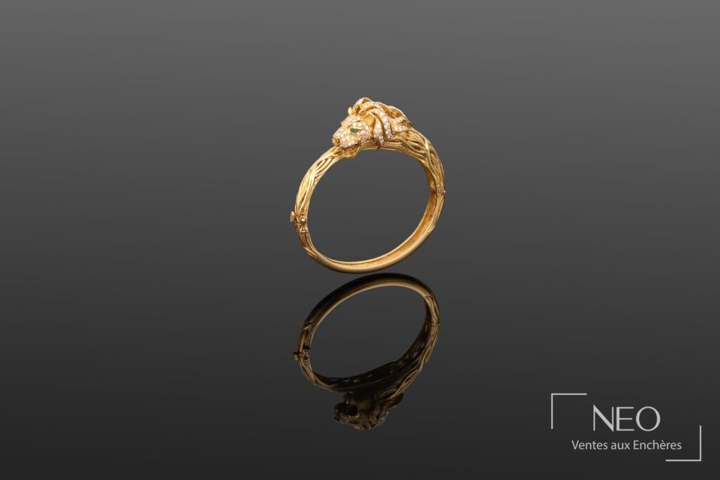 Bracelet jonc en or jaune avec tête de lion et reflet sur fond sombre