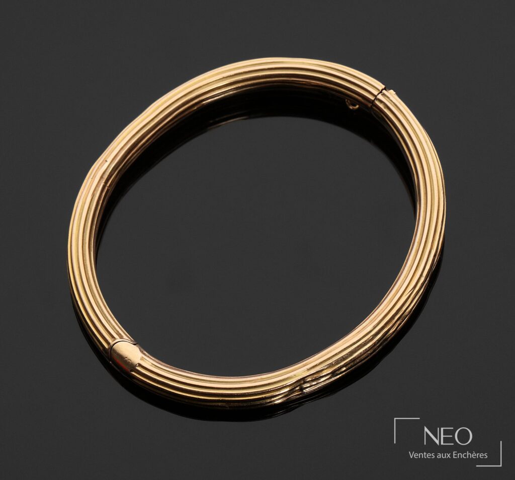 Bracelet jonc ouvrant cannelé en or jaune vu de face sur fond sombre