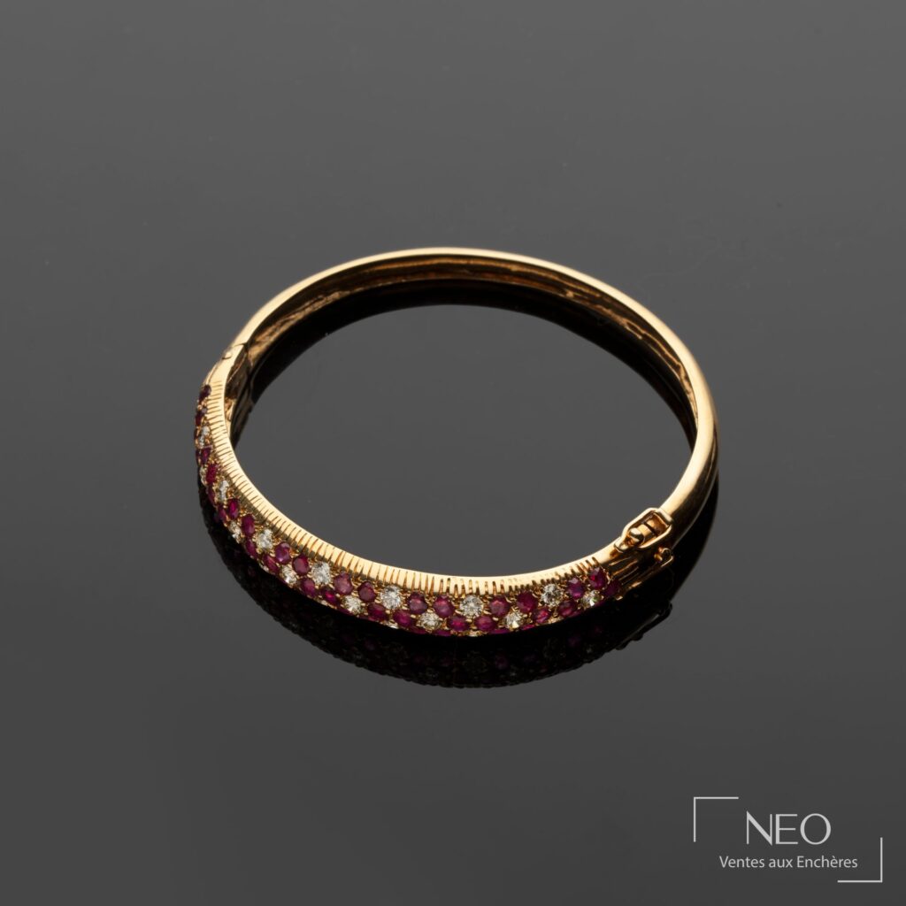 Bracelet jonc en or jaune orné de diamants et de rubis sur fond sombre