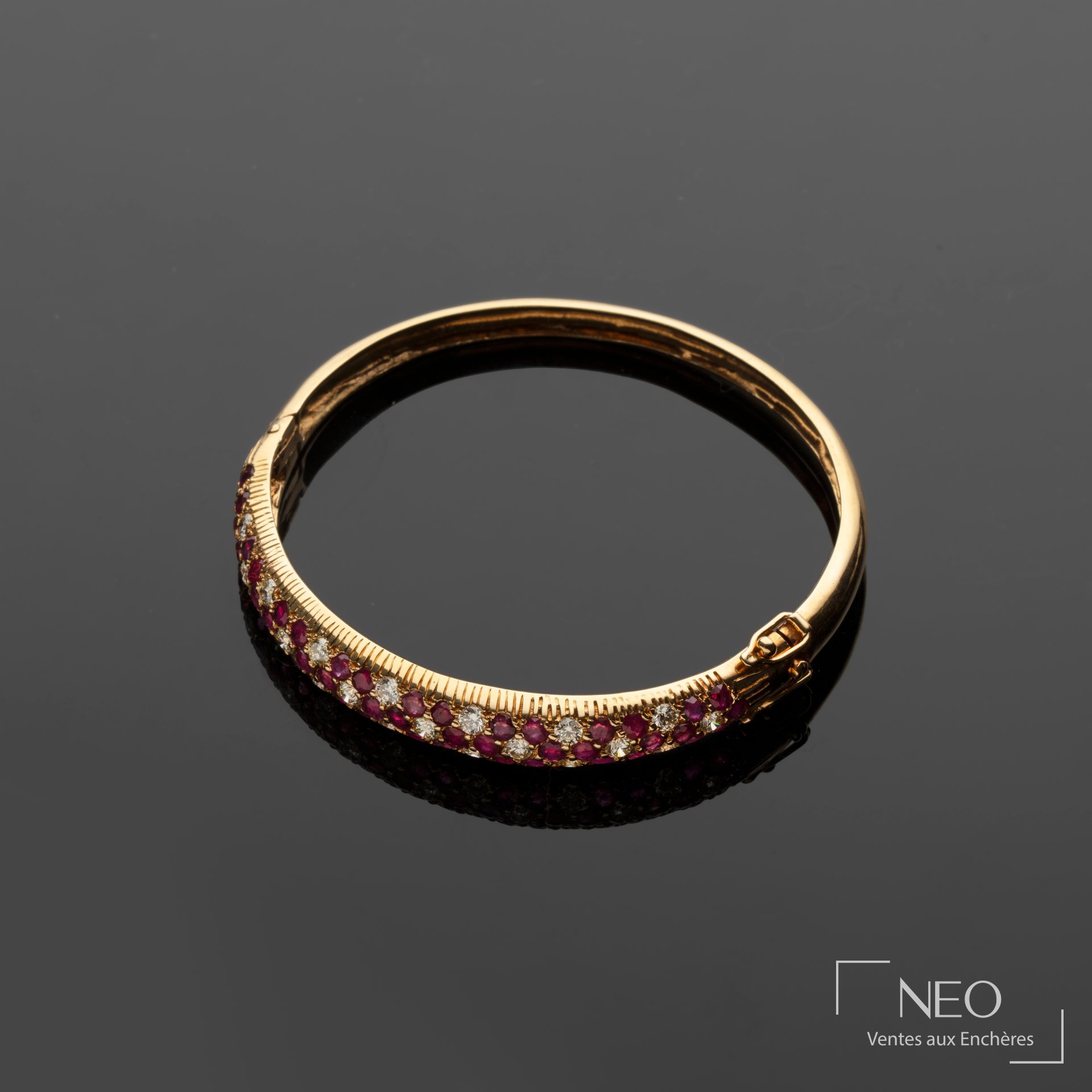 Bracelet jonc en or jaune orné de diamants et de rubis sur fond sombre