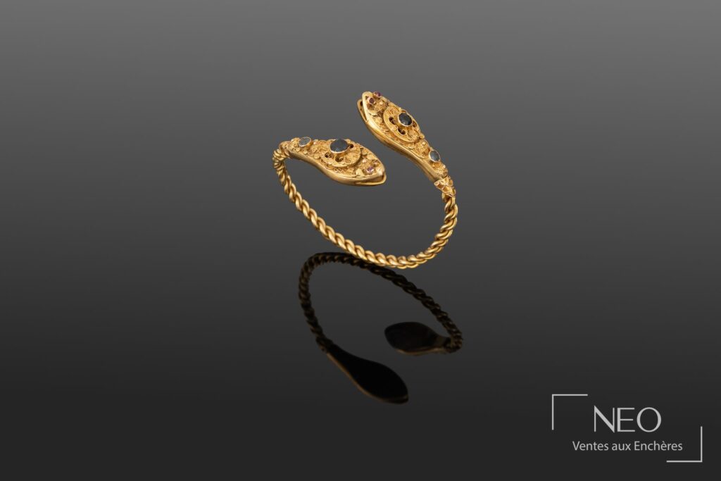 Bracelet jonc torsadé en or jaune avec deux têtes de serpents serties de saphirs et rubis